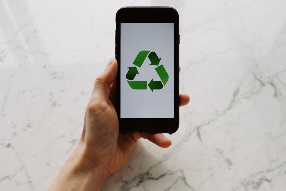 Anonymous person showing recycle symbol on smartphone