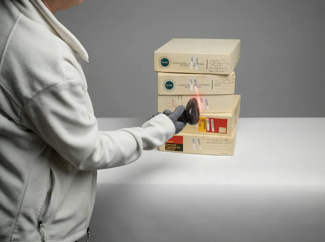 A customer handing a packed box of videotapes to a CVS photo counter